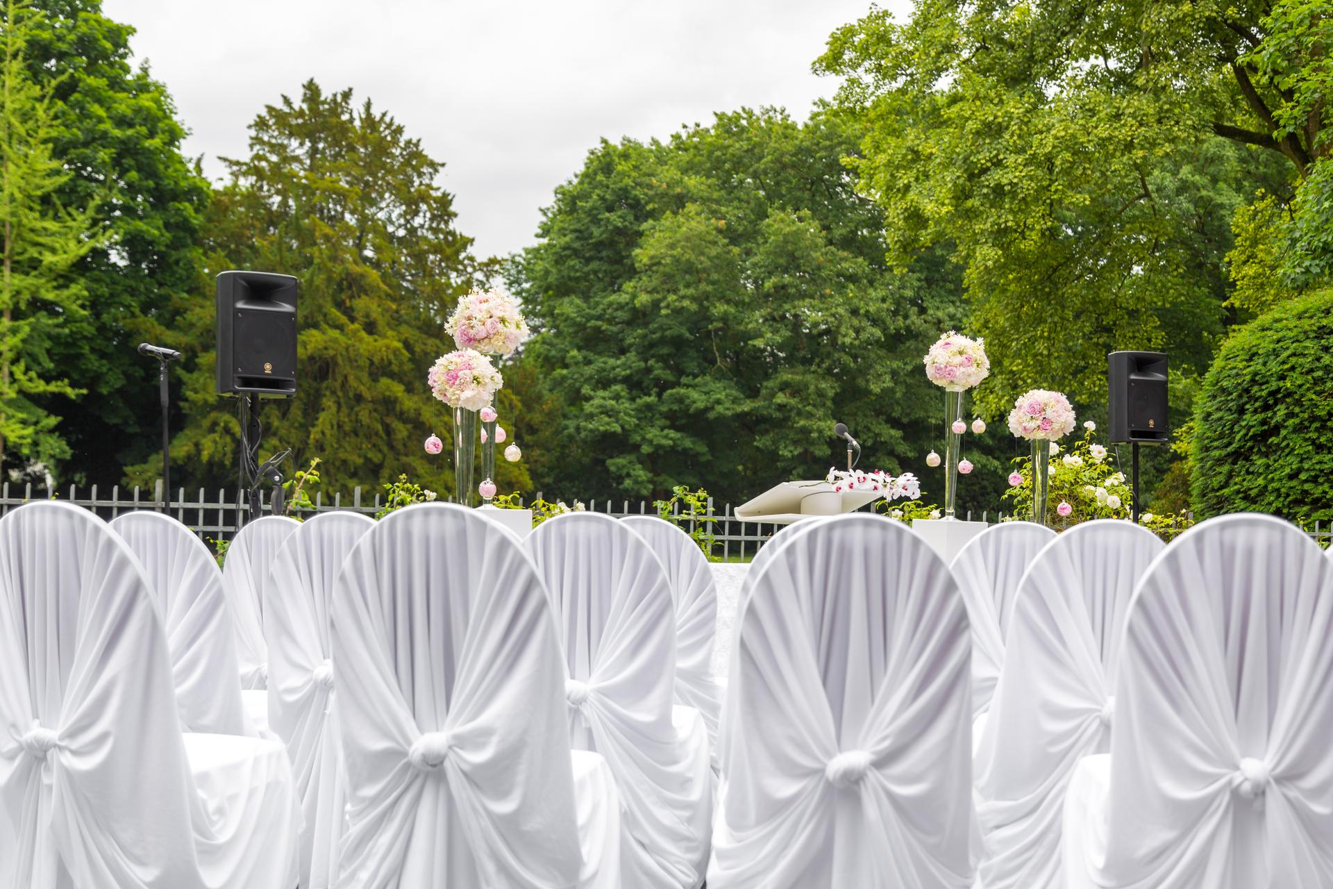 Scenery of the wedding ceremony in the park. White frame decorated with flowers. Ceremony in white style